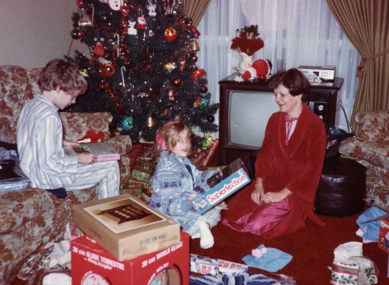default-184 An old photograph showing a boy, a girl and their mother opening gifts on Christmas morning.