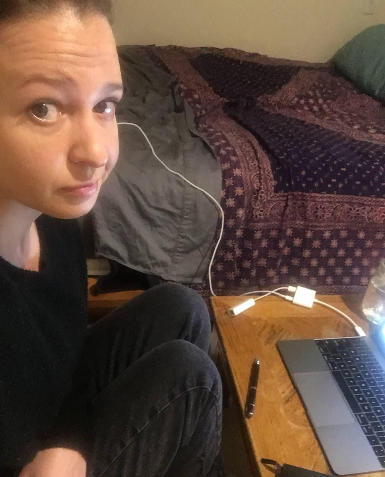default-35 A woman poses for a selfie while sitting next to her laptop and bed.
