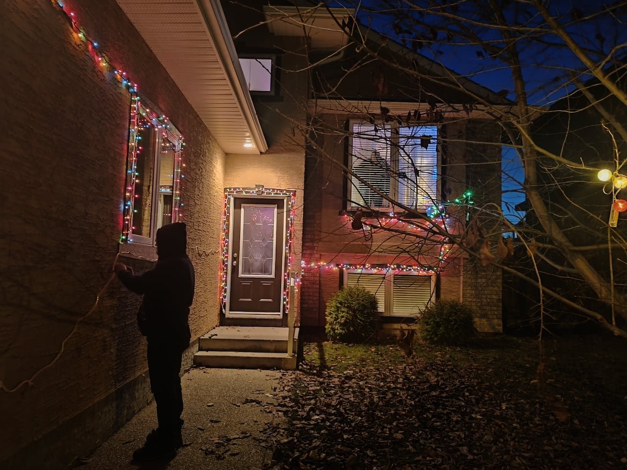 Lights sparkle on the edges of a house lit at night.