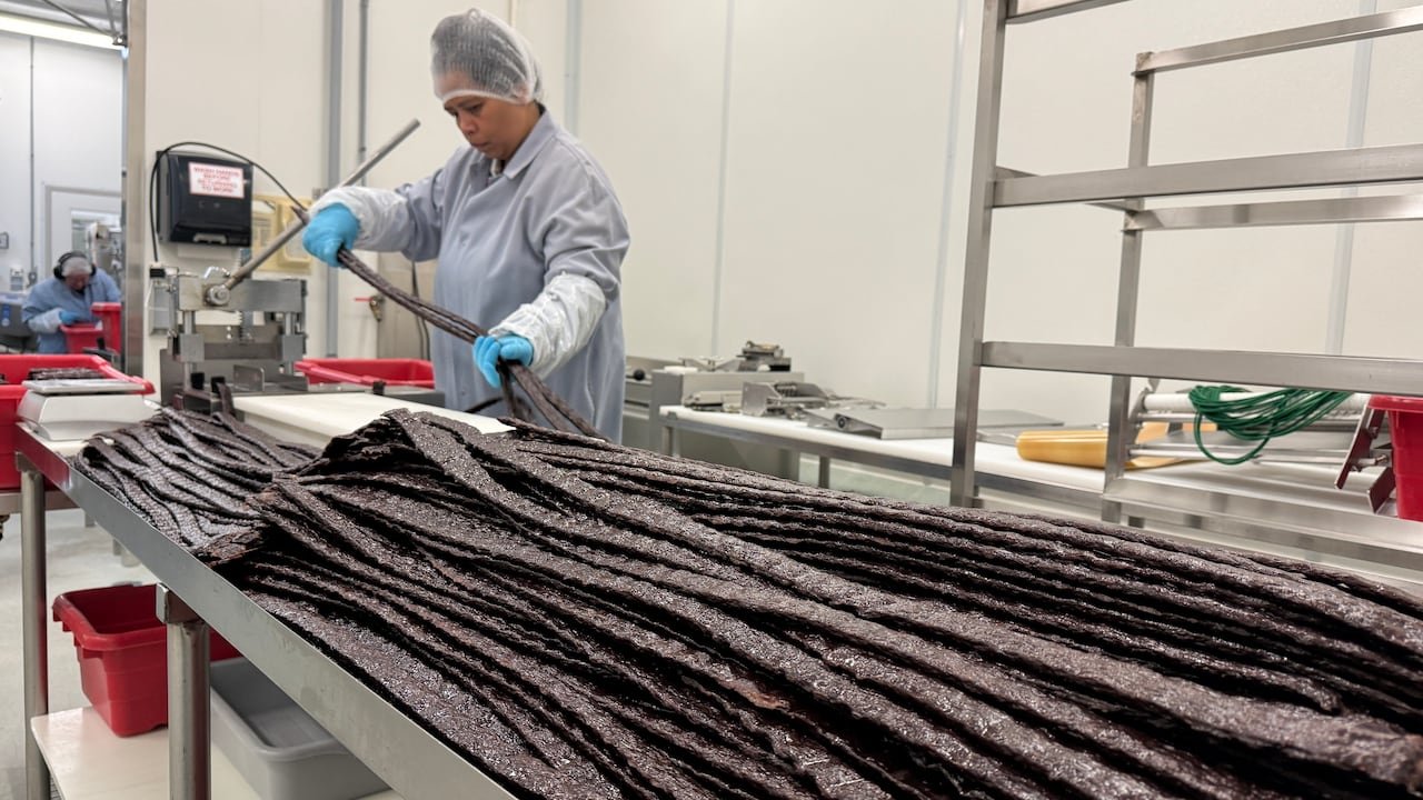 default-676 A woman in protective wear hold long strands of brown material.